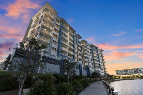 a large white building next to a body of water at Aquarius Kawana in Kawana Waters