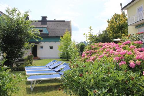 a row of blue benches in a yard with flowers at Blaues Haus Ferienwohnung Bodensdorf Ossiacher See Gerlitzen Alpe in Bodensdorf
