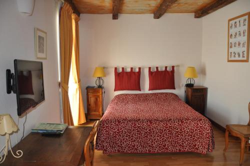 a bedroom with a bed with red pillows and a television at Hôtel du Donjon in Aulnay