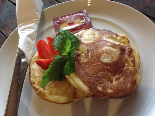 a plate of food with a pancake with fruit on it at Jempiring Homestay in Ubud