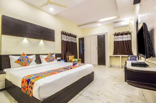 Schlafzimmer mit einem Bett, einem Schreibtisch und einem TV in der Unterkunft FabHotel Crown Suites in Bangalore