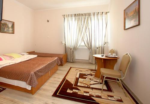 um quarto com uma cama, uma mesa e uma cadeira em Kompleks Perła em Lomza
