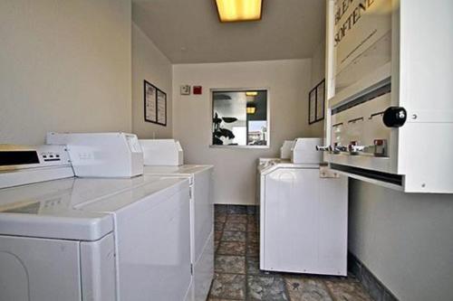 a kitchen with white appliances in a room at Hilltop Inn & Suites in Victorville