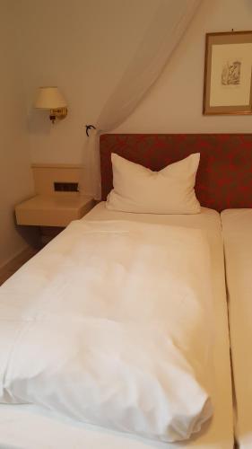 Cama blanca con cabecero rojo y almohadas blancas en Gasthaus Krone, en Wiesentheid