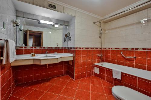 La salle de bains est pourvue de 2 lavabos, d'une baignoire et d'un miroir. dans l'établissement Central Hotel, à Bursa