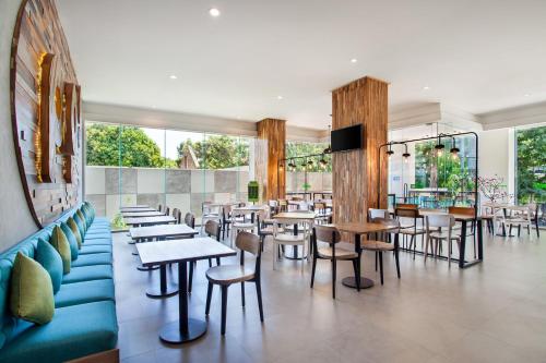 a restaurant with tables and chairs and windows at POP! Hotel Pemuda Semarang in Semarang