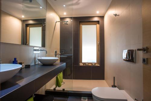 a bathroom with two sinks and a toilet and a shower at Modern Apartment with sea view in Saronida in Anavissos