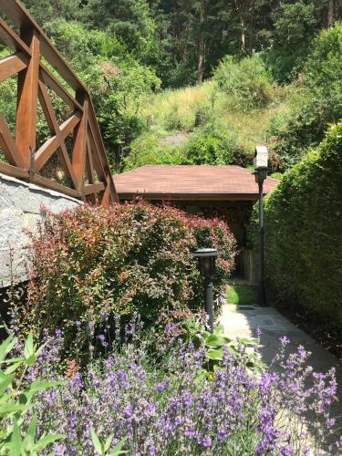 a garden with purple flowers and a wooden bridge at Vila Rila Samokov in Samokov