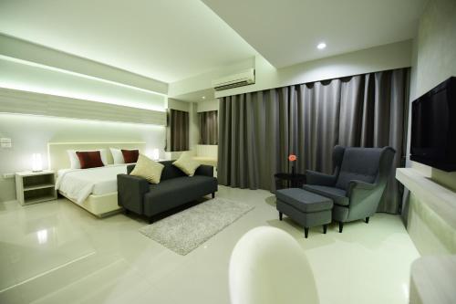 ナコーンパトムにあるTrendy Hotelのベッドとソファと椅子があるホテルの部屋