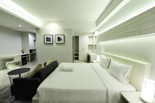 een slaapkamer met een groot wit bed en een bank bij Trendy Hotel in Nakhon Pathom