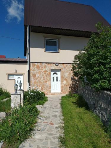 a house with a white door and a stone walkway at Durmitorske zore in Žabljak