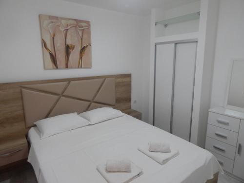 a bedroom with a white bed with two towels on it at Apartment Iv in Kotor