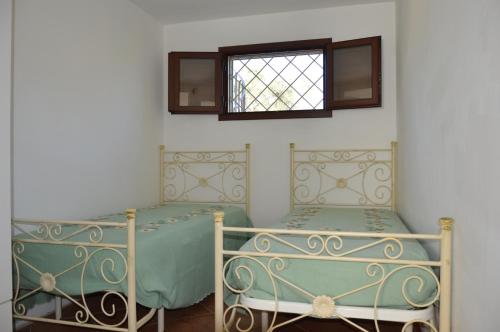 two beds in a room with a window at Portoselvaggio Villa Martina in Santa Caterina di Nardò