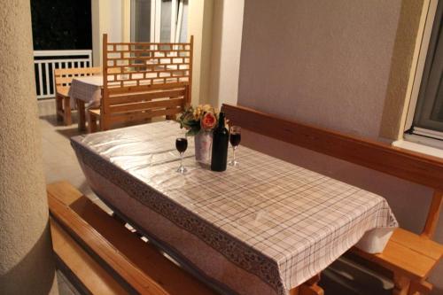 einen Tisch mit zwei Gläsern Wein und Blumen darauf in der Unterkunft Vila Apartment in Poljica