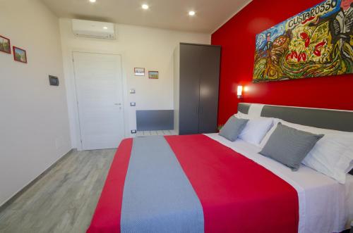 een slaapkamer met een groot bed met een rode muur bij Gustarosso Rooms in Sarno
