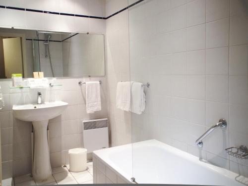 a white bathroom with a sink and a tub and a toilet at Hôtel Concordia Le Mans Centre Gare in Le Mans