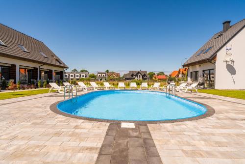 a swimming pool with chairs in a yard at Zielony Zakątek in Łeba