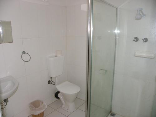 a bathroom with a toilet and a glass shower at Palms Motel Footscray in Melbourne