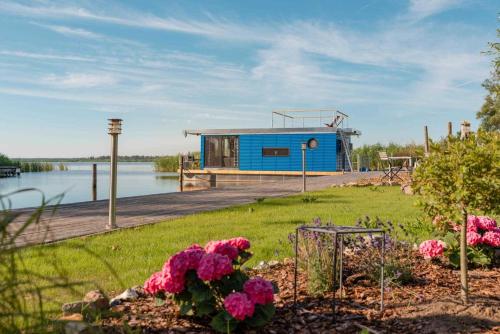 una casa azul en un muelle junto a un cuerpo de agua en Hafenresort Karnin, en Karnin