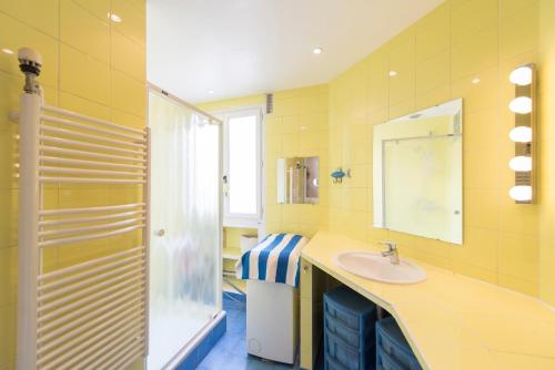 La salle de bains jaune est pourvue d'un lavabo et d'un miroir. dans l'établissement Veeve - Musical retreat in the 15th, à Paris