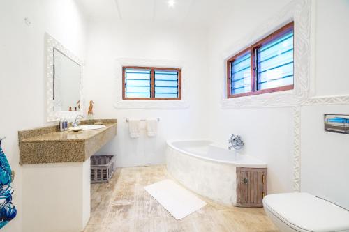 a bathroom with a tub and a sink and a toilet at Nomad Beach Resort in Diani Beach