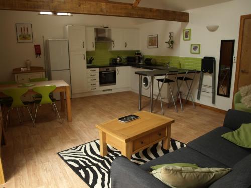 cocina y sala de estar con sofá y mesa en The Courtyard at Lodge Farm, en Norwich