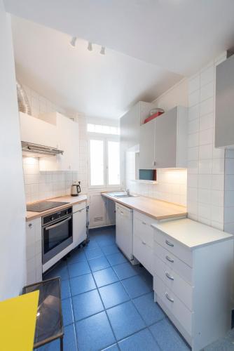 Il comprend une cuisine avec des placards blancs et du carrelage bleu. dans l'établissement Veeve - Musical retreat in the 15th, à Paris