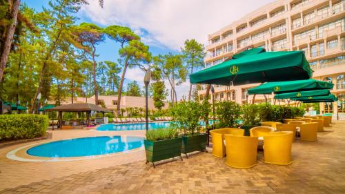 a patio with chairs and umbrellas next to a pool at Kobuleti Georgia Palace Hotel & Spa in K'obulet'i