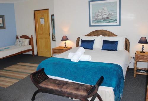 a bedroom with a large bed and a chair at Cheetah Lodge Guest House in Hartenbos