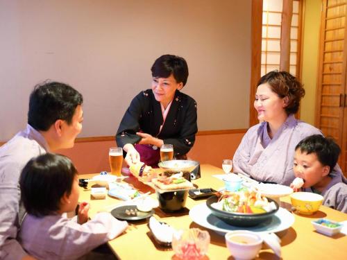 a group of people sitting around a table eating food at Tenku Yubo Seikaiso in Beppu