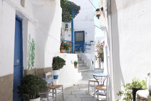 a narrow alley with chairs and tables and a blue door at Living Theros Luxury Suites in Kardiani