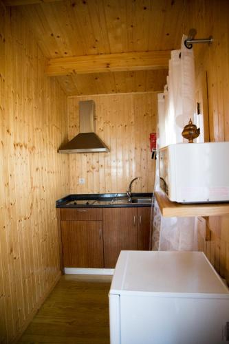 a kitchen with wooden walls and a white refrigerator at Quinta Da Fontinha in Celorico de Basto
