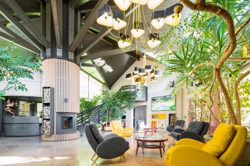 a lobby with chairs and tables and plants at Le Bois Dormant-Hôtel Restaurant & Spa Logis Hôtel in Champagnole