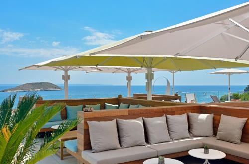 a patio with a couch and umbrellas and the ocean at INNSiDE by Meliá Calviá Beach in Magaluf