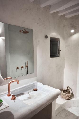 a white bathroom with a sink and a mirror at Living Theros Luxury Suites in Kardiani