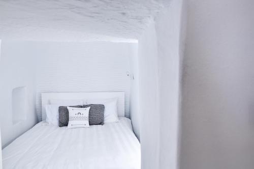 a small white bed with two pillows on it at Living Theros Luxury Suites in Kardiani