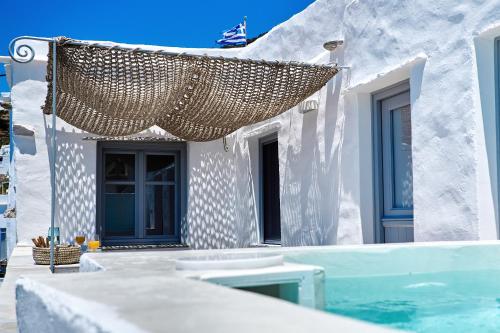 uma casa branca com uma piscina e um guarda-chuva de palha em Living Theros Luxury Suites em Kardhianí