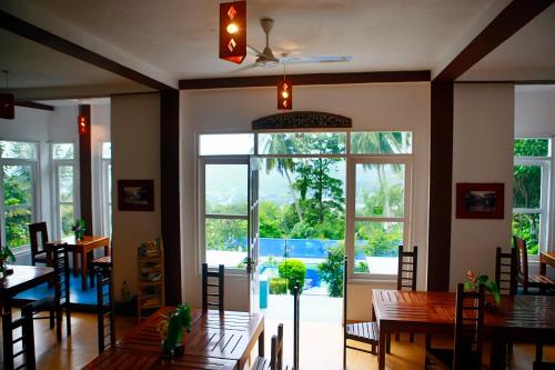 a dining room with tables and chairs and a large window at The Change Hotel in Kandy