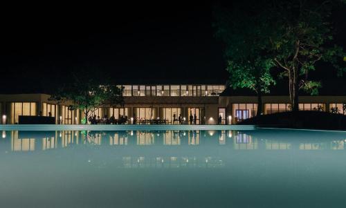 a building with a swimming pool at night at Saraca Resort & Spa Corbett in Garjia
