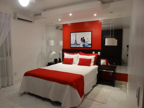 a bedroom with a large bed with a red wall at Pousada Solar Dom Kido in Torres