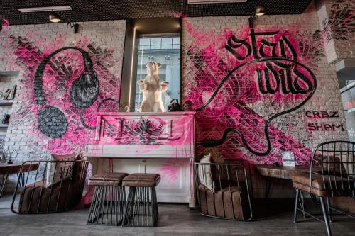 a room with a pink wall with a statue on a piano at ibis Styles Lausanne Center MadHouse in Lausanne