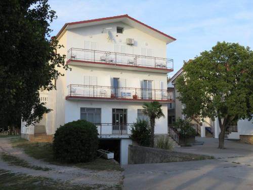 a large white building with balconies and trees at Apartmani MM in Starigrad-Paklenica