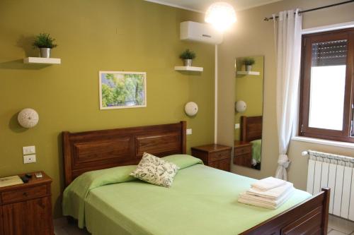 ein grünes Schlafzimmer mit einem Bett und einem Spiegel in der Unterkunft Casa Mita in Pulsano