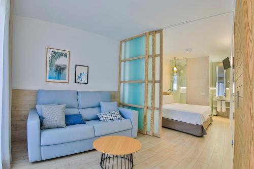 a living room with a blue couch and a bedroom at Apartamentos 525 in Los Alcázares