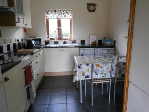 a kitchen with white cabinets and a table with chairs at Lake View in Mellis