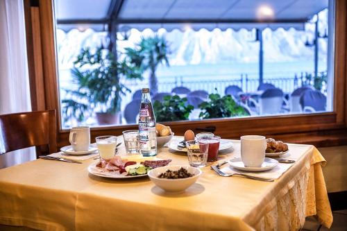 a table with plates of food and a bottle of water at Hotel Astoria - 3stelle S in Malcesine
