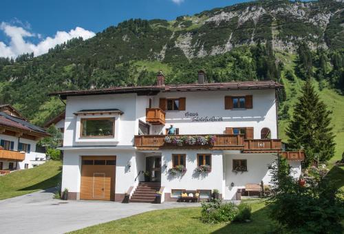 a large white building with a mountain in the background at Haus Schrofenstein in Lech am Arlberg