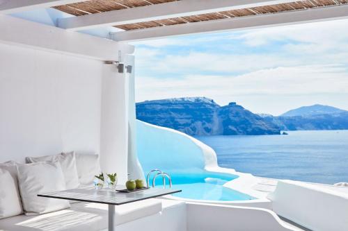 a room with a view of the water and mountains at Katikies Santorini - The Leading Hotels Of The World in Oia