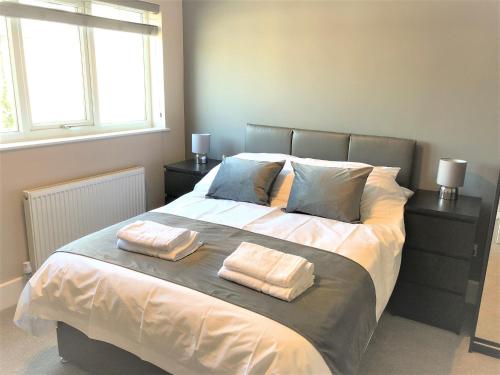 een slaapkamer met een groot bed en 2 handdoeken bij Guineas House in Newmarket
