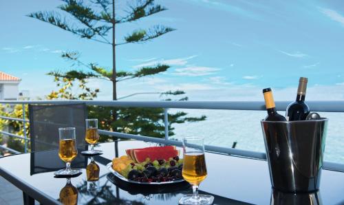 a table with two glasses of wine and a bowl of fruit at Kiveri Luxurious Seaside Apartment in Kiveri